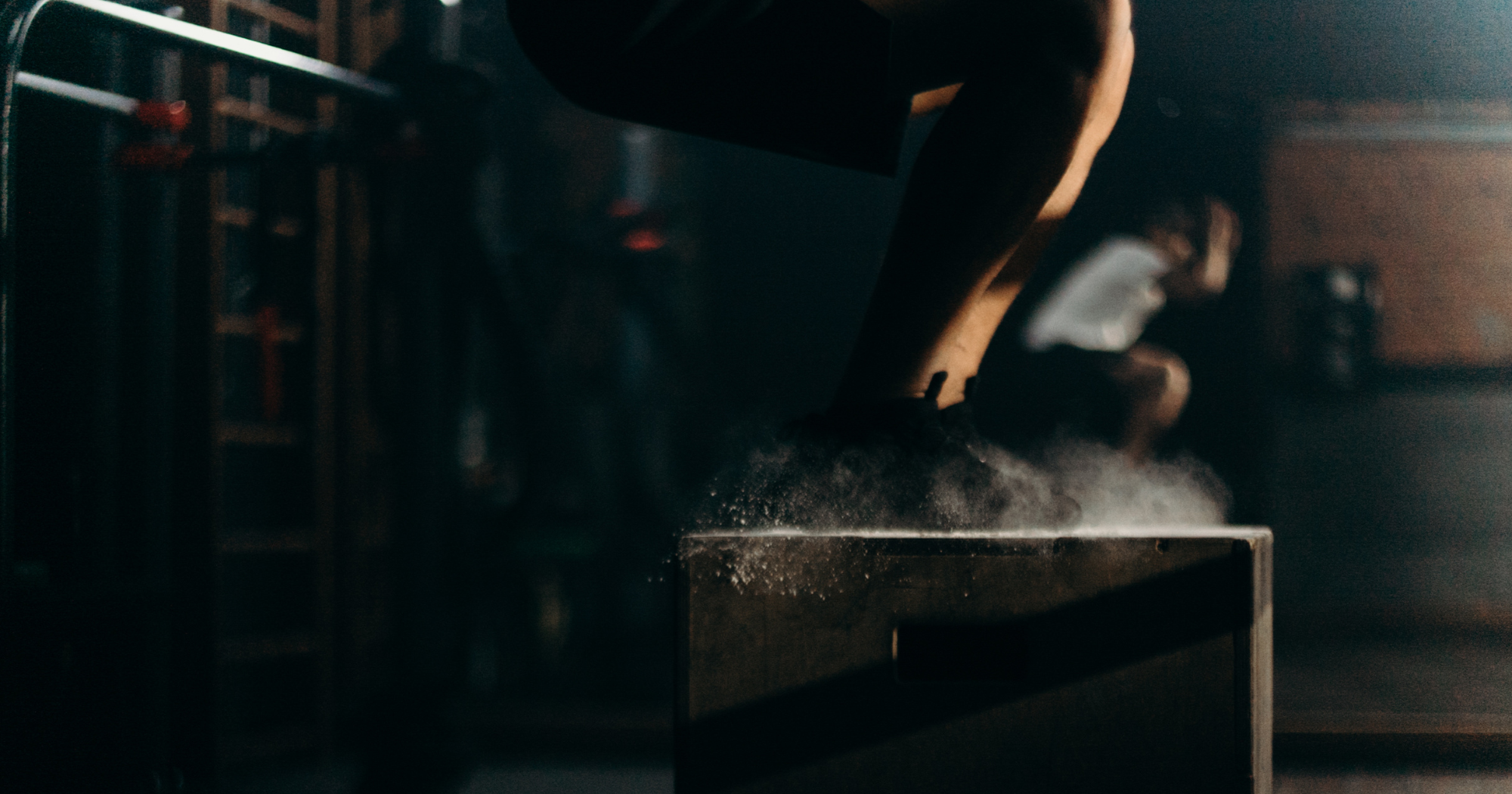 a person jumping onto a box in a gym